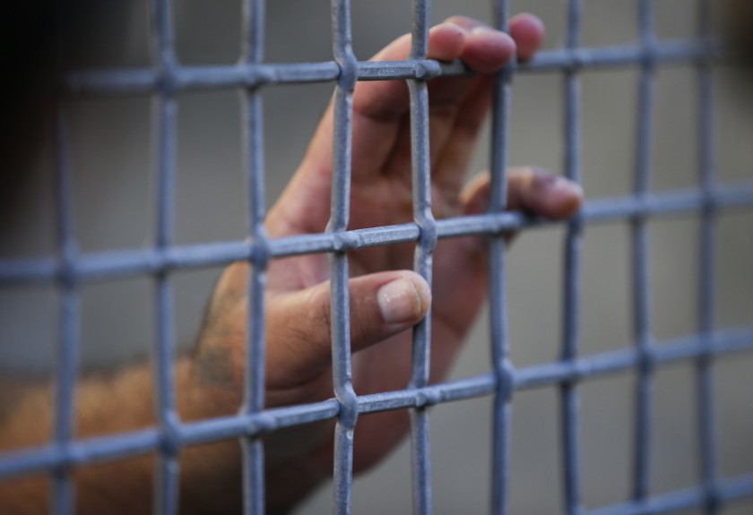 A condemned prisoner touches the mesh fence in the exercise yard during a media tour at San Quentin State Prison in this undated photo. (Mark Boster / Los Angeles Times)