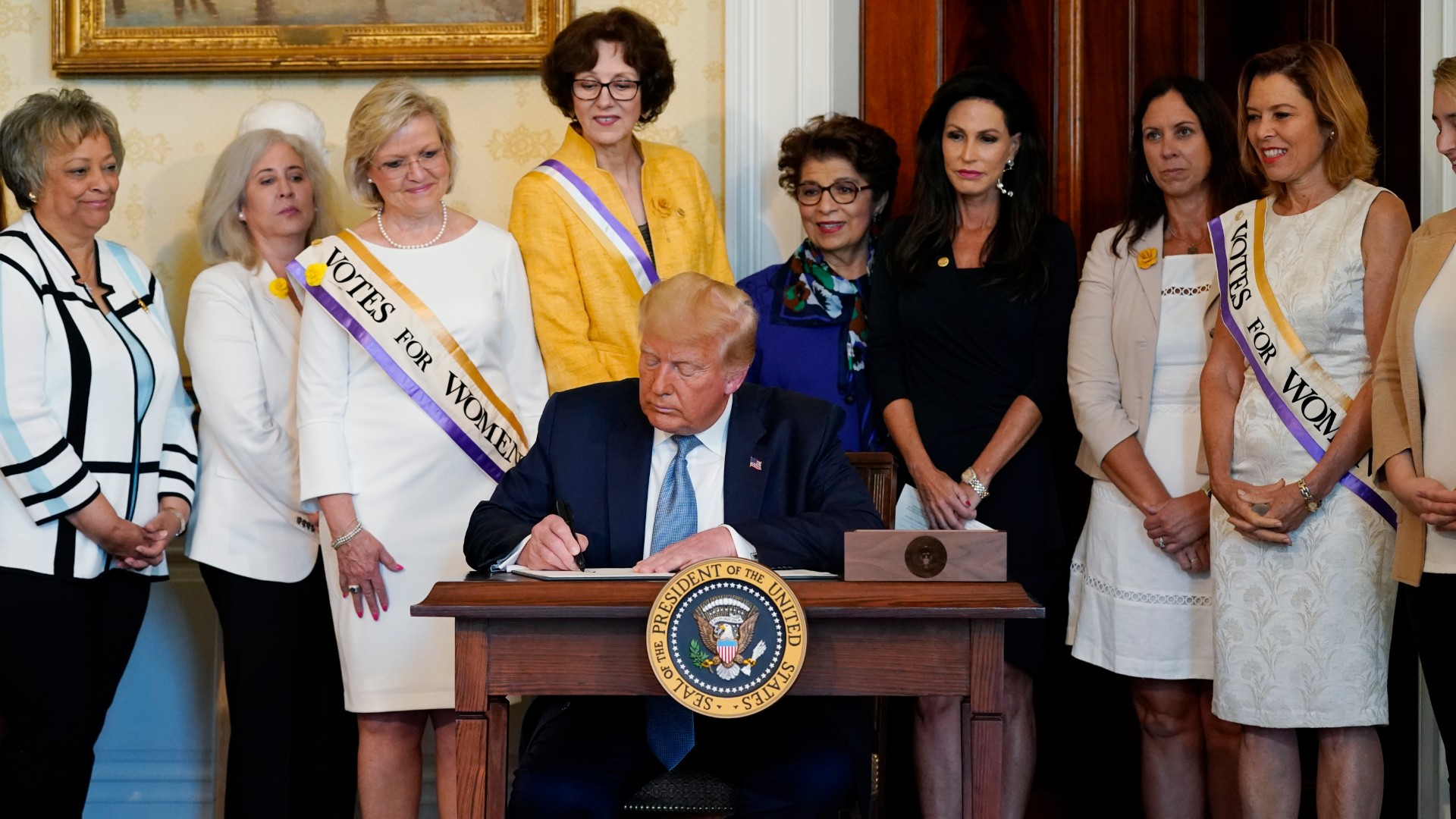 President Donald Trump signs a proclamation recognizing the 100th anniversary of the ratification of the 19th Amendment, Tuesday, Aug. 18, 2020, in the Blue Room of the White House in Washington. (AP Photo/Patrick Semansky)