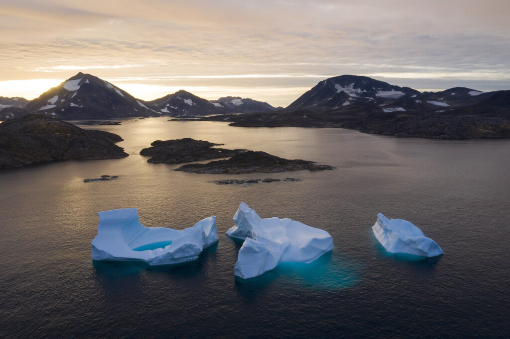 In this Aug. 16, 2019 file photo, icebergs float away as the sun rises near Kulusuk, Greenland. According to a study released on Thursday, Aug. 20, 2020, Greenland lost a record amount of ice during an extra warm 2019, with the melt massive enough to cover California in more than four feet (1.25 meters) of water. (AP Photo/Felipe Dana, File)