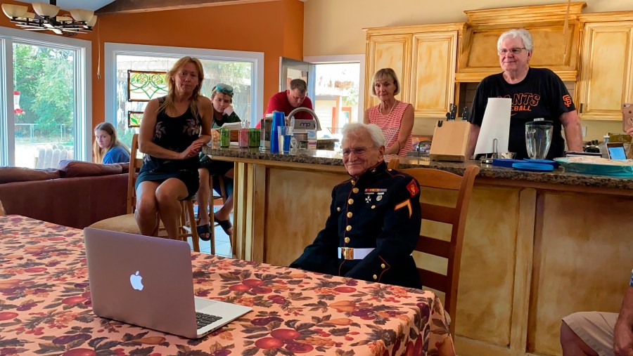 Jerry Pedersen, center, watches a livestream of today's ceremony of the 75th anniversary of the end of WWII at his son's home in West Sacramento. (AP Photo/Terry Chea)