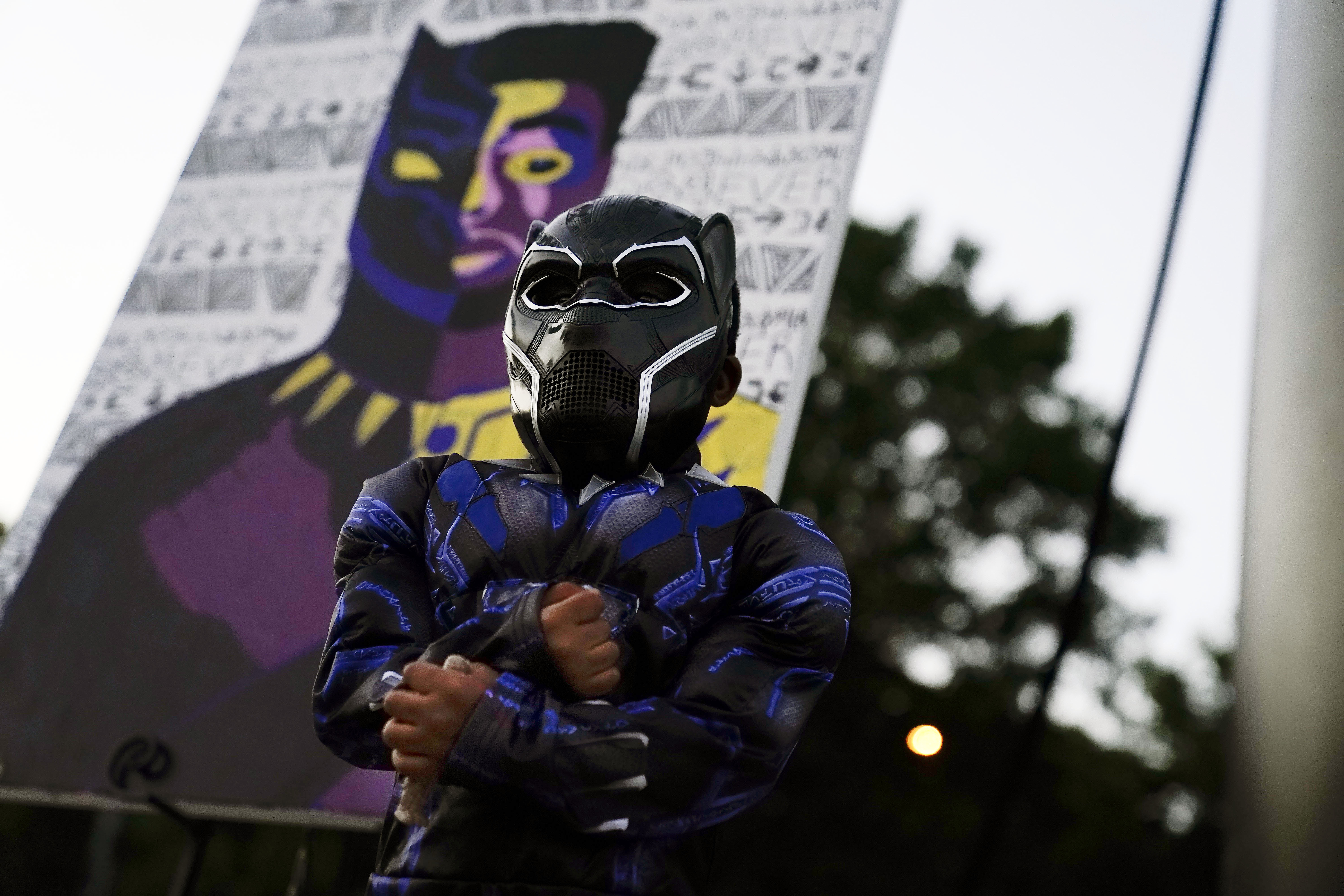 Mason Wilkes, 4, of South Carolina, poses for his father in a Black Panther costume, in front of a painting during a Chadwick Boseman Tribute on Thursday, Sept. 3, 2020, in Anderson, S.C. (AP Photo/Brynn Anderson)