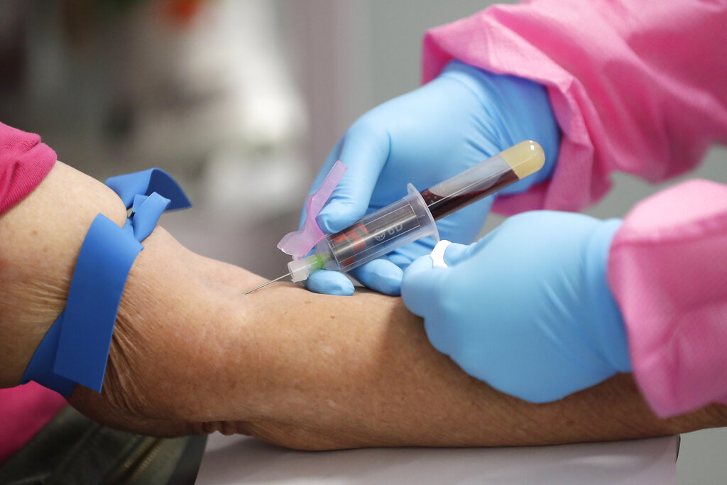 In this Tuesday, May 5, 2020 file photo, a health worker draws blood from a patient for a COVID-19 coronavirus antibody test in DeLand, Fla. (AP Photo/John Raoux)