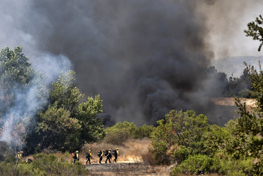 Los Angeles Fire Department firefighters hike into the Sepulveda Basin to fight a brush fire in the Sherman Oaks area of Los Angeles, Sunday, Sept. 6, 2020. (AP Photo/Richard Vogel)