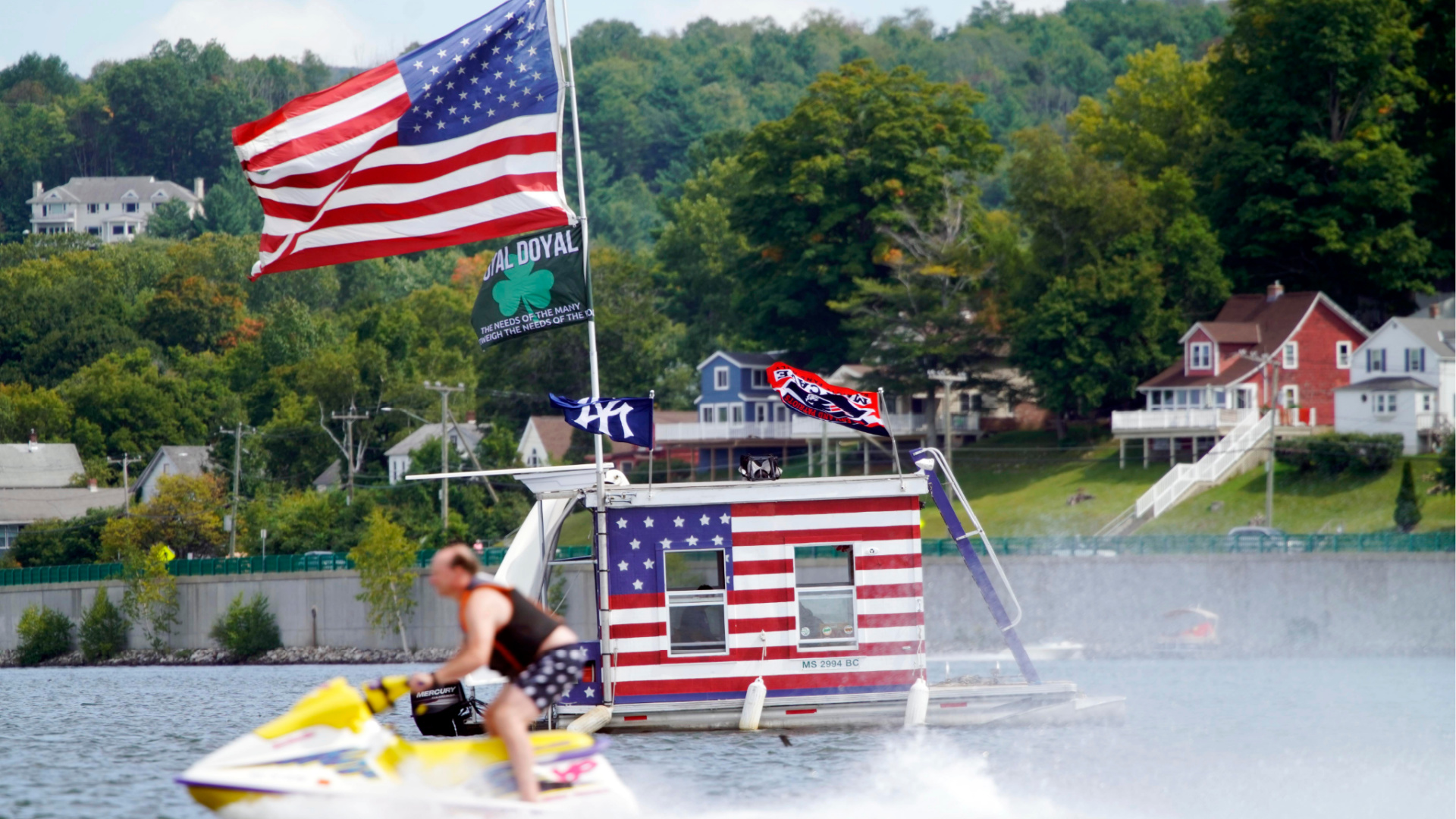 A jet skier passes a patriotic shanty-boat owned by AJ Crea on Pontoosuc Lake on Labor Day in Pittsfield, Mass., Monday, Sept. 7, 2020. (Ben Garver/The Berkshire Eagle via AP)