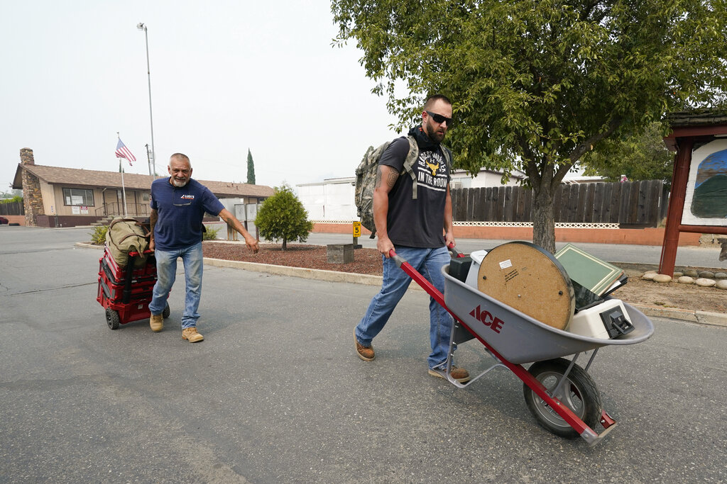 Two men take out their belongings on wheel barrows during a mandatory evacuation due to the Creek Fire Sept. 7, 2020, in Auberry, Calif. (AP Photo/Marcio Jose Sanchez)