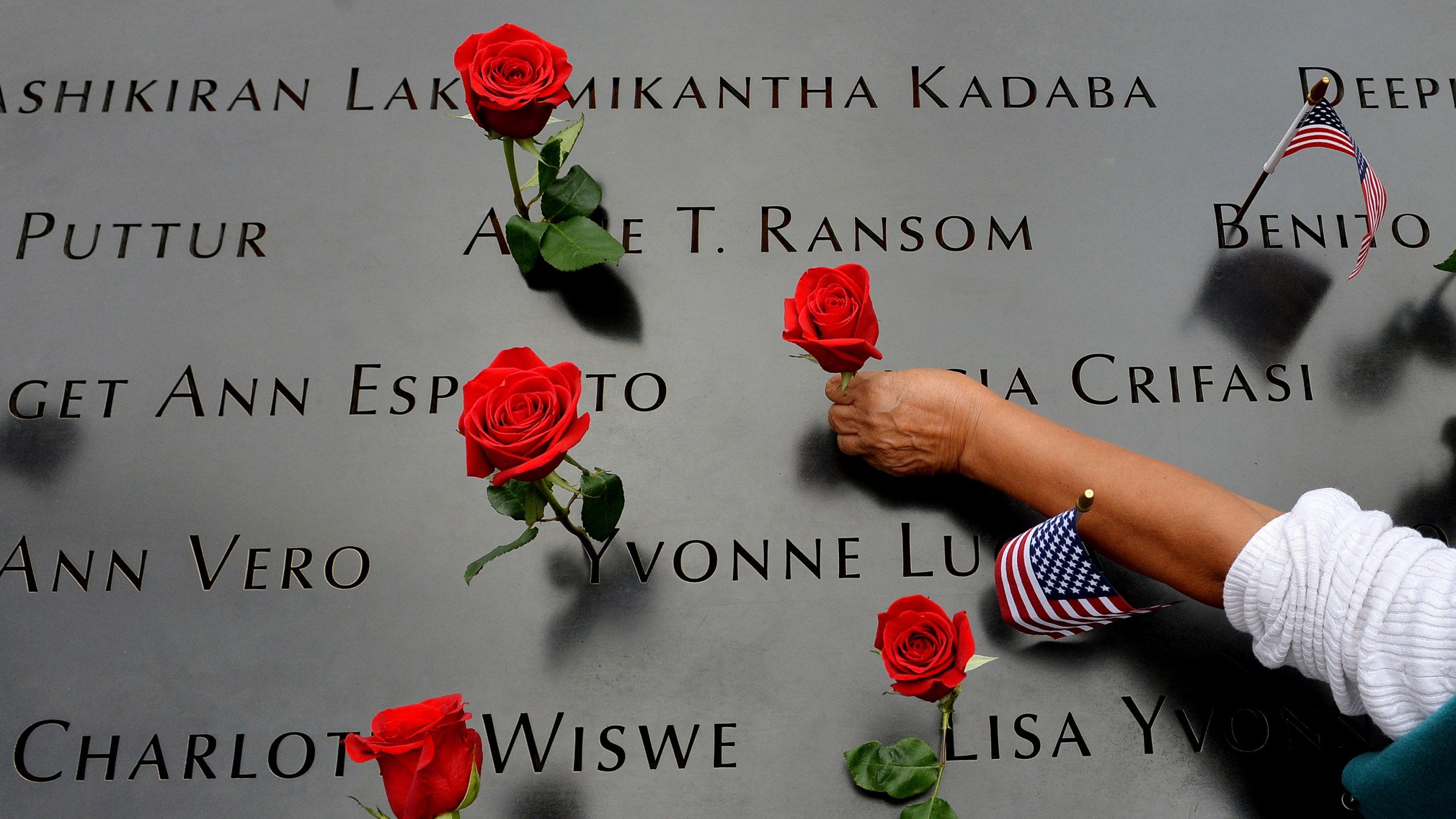 In this Sept. 11, 2014, photo, a woman places flowers in the inscribed names along the edge of the North Pool during memorial observances on the 13th anniversary of the Sept. 11, 2001, terror attacks on the World Trade Center in New York. (AP Photo/Justin Lane, Pool, File)