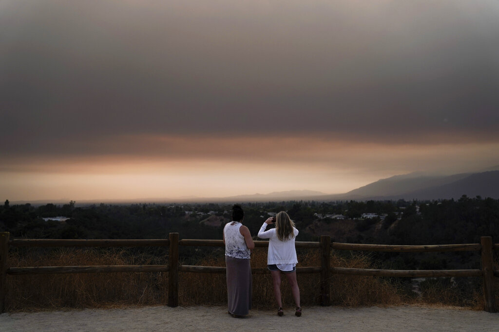 Two people watch smoke generated by the Bobcat Fire in San Dimas on Sept. 9, 2020. (AP Photo/Jae C. Hong)