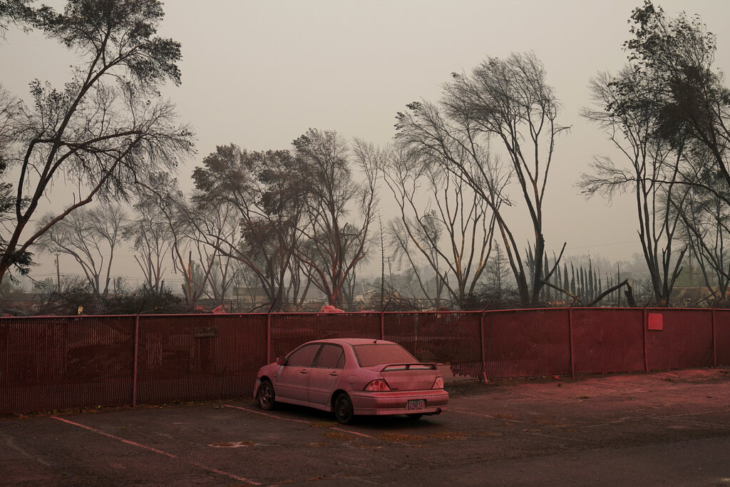 Pink fire retardant covers a car in an area destroyed by the Almeda Fire, Friday, Sept. 11, 2020, in Talent, Ore. (AP Photo/John Locher)