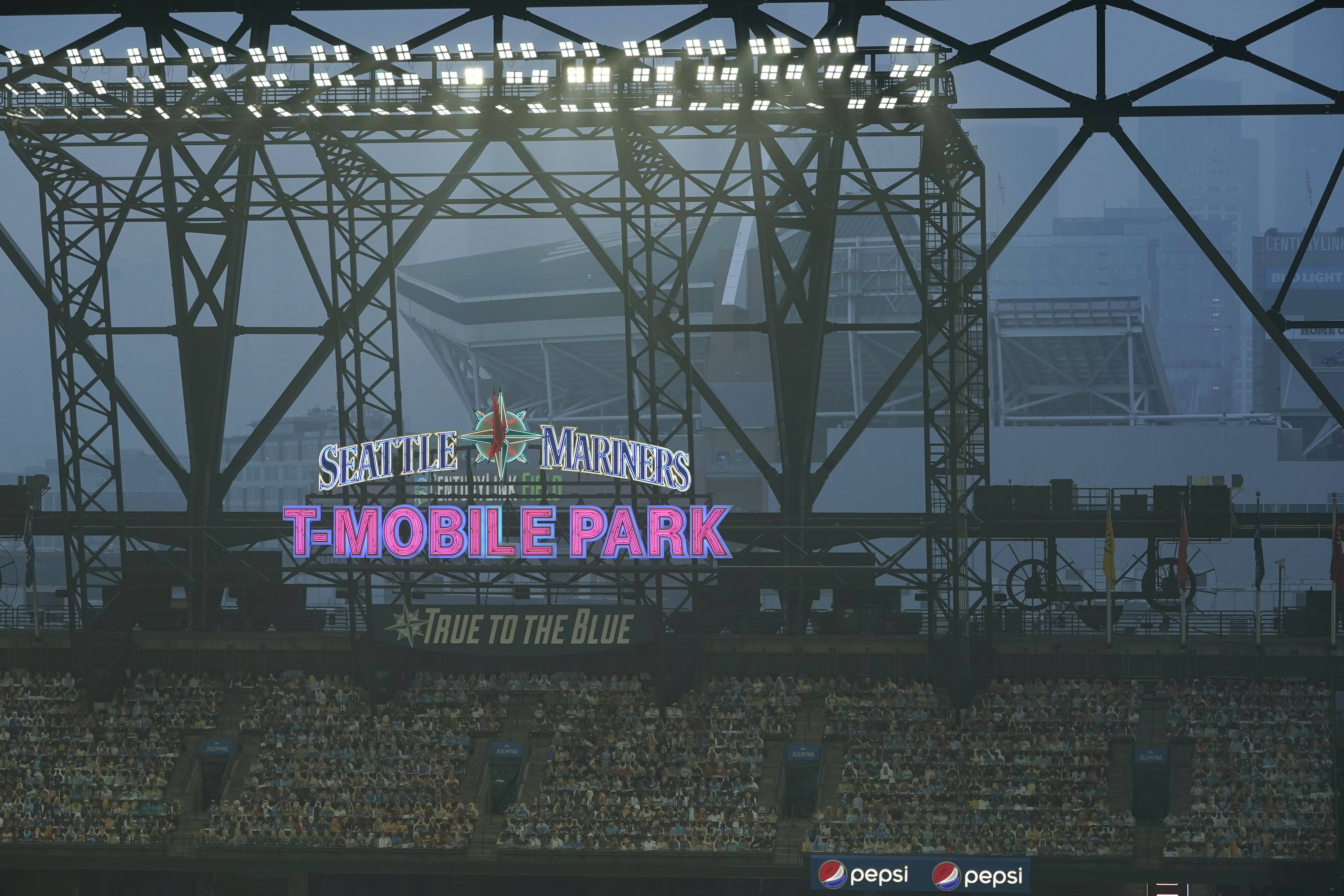 Smoke from wildfires fills the air at T-Mobile Park as photos of fans are displayed in the left field bleachers and CenturyLink Field is visible behind the ballpark sign during the second baseball game of a doubleheader between the Seattle Mariners and the Oakland Athletics, Sept. 14, 2020, in Seattle. (Ted S. Warren / Associated Press)