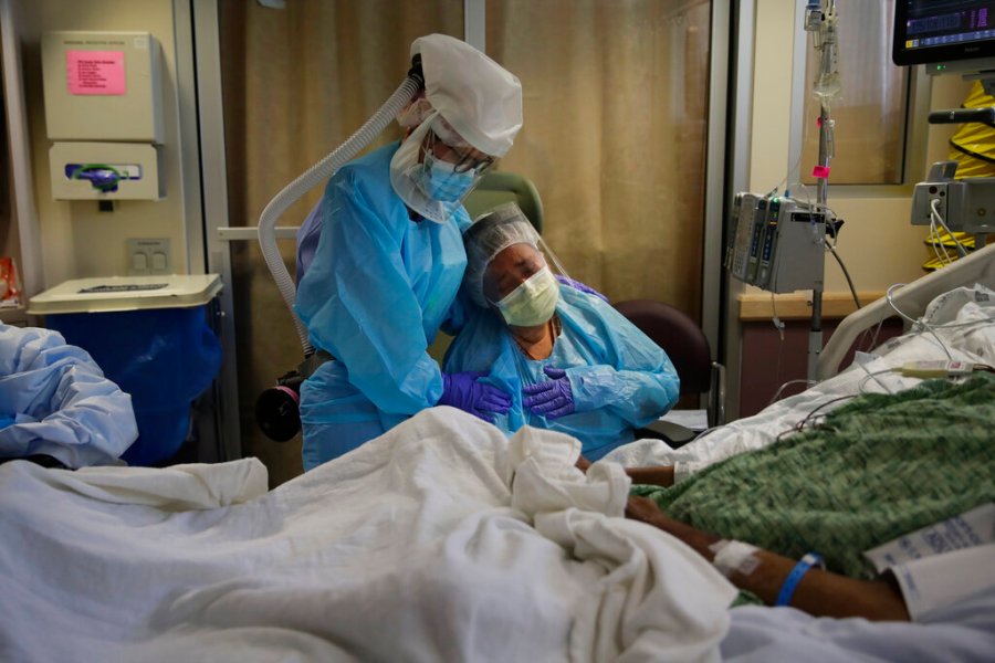 In this July 31, 2020, file photo, Romelia Navarro, right, is comforted by nurse Michele Younkin, left, as she weeps while sitting at the bedside of her dying husband, Antonio Navarro, in St. Jude Medical Center's COVID-19 unit in Fullerton. (AP Photo/Jae C. Hong, File)