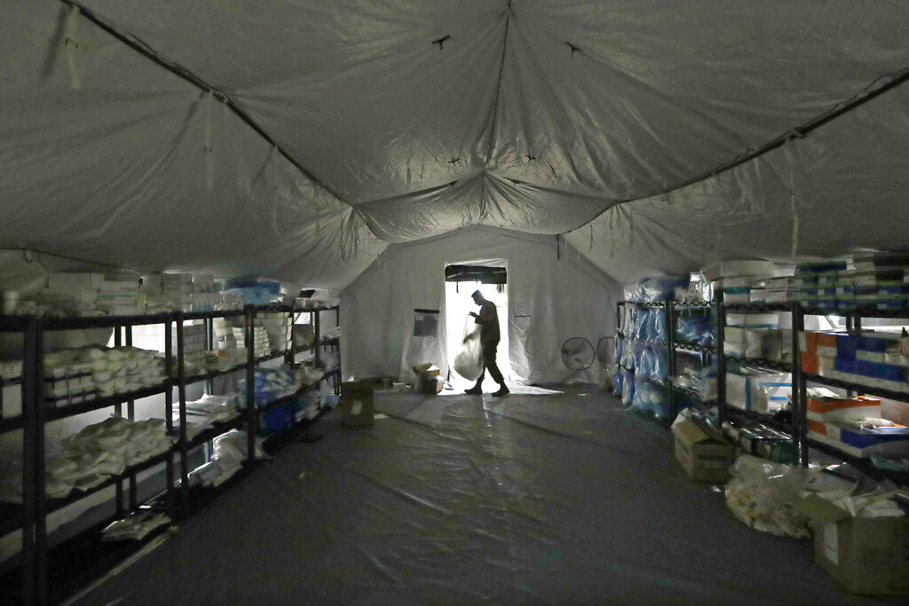 In this March 31, 2020, file photo a U.S. Army soldier walks inside a mobile surgical unit being set up by soldiers from Fort Carson, Col., and Joint Base Lewis-McChord (JBLM) as part of a field hospital inside CenturyLink Field Event Center, in Seattle. (AP Photo/Elaine Thompson, File)