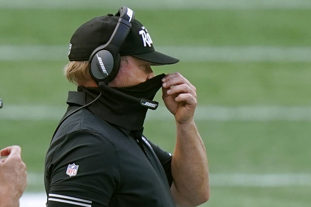 Las Vegas Raiders head coach Jon Gruden adjusts his protective mask along the sideline in the second half of an NFL football game against the New England Patriots on Sept. 27, 2020, in Foxborough, Mass. (AP Photo/Steven Senne)