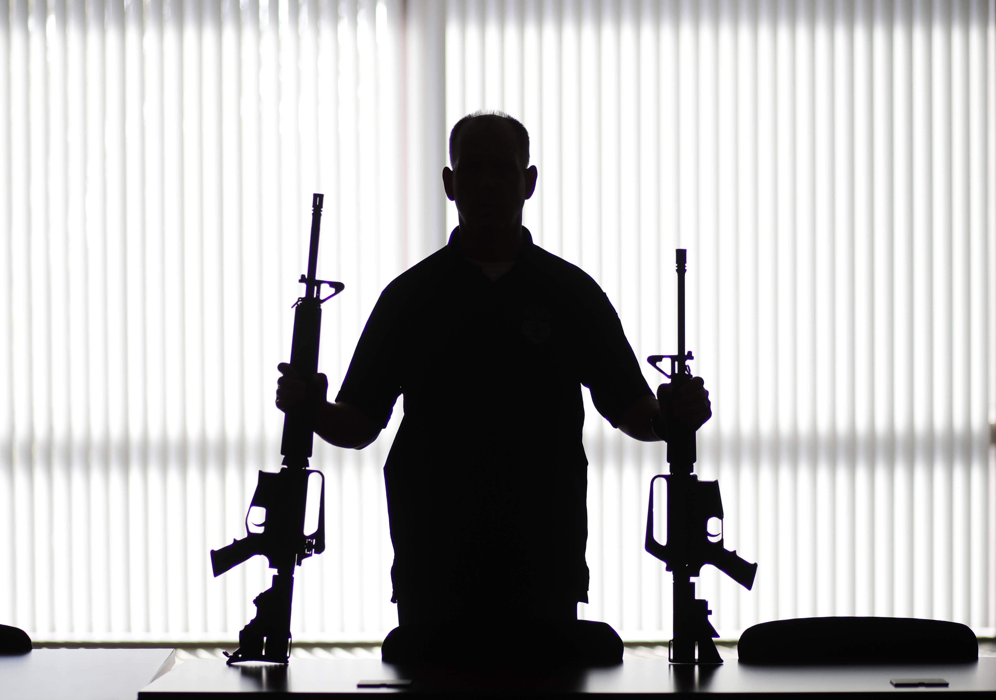 In this Aug. 29, 2017, file photo, an ATF agent poses with homemade rifles, or "ghost guns," at an ATF field office in Glendale. (Jae C. Hong/Associated Press)