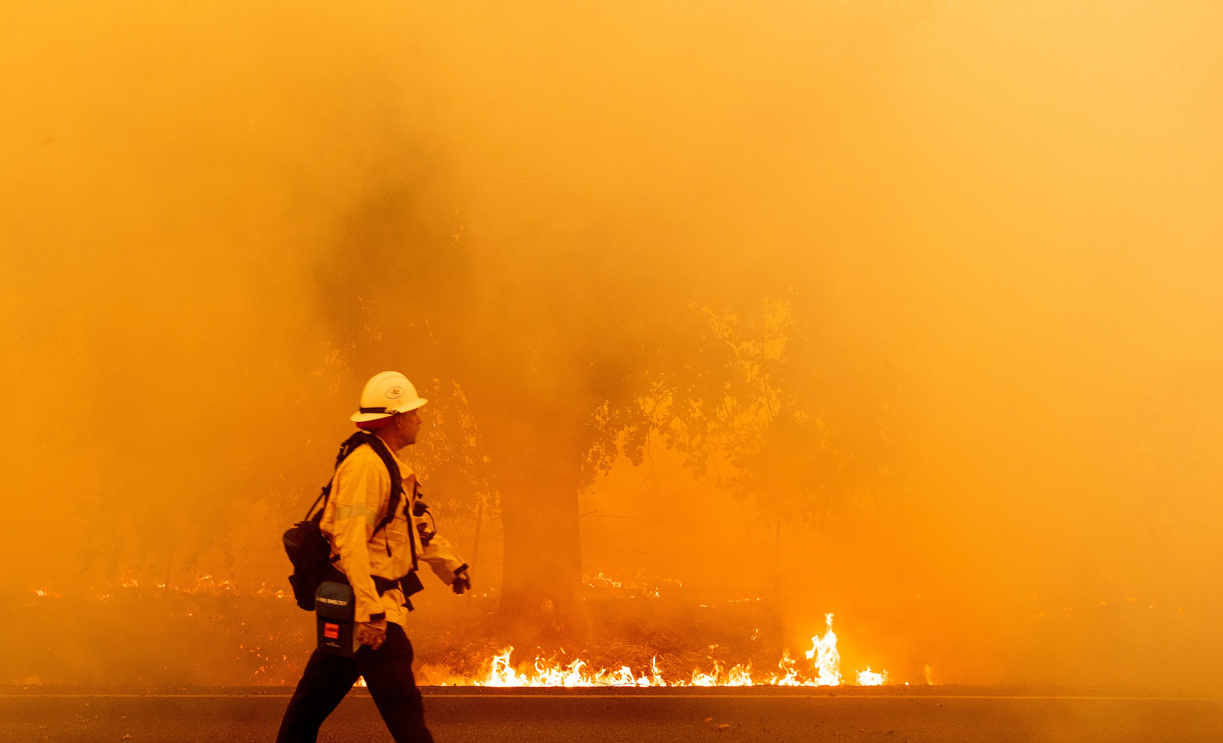 A Pacific Gas and Electric firefighter walks down a road as flames approach in Fairfield, Calif. during the LNU Lightning Complex fire on Aug. 19, 2020. (JOSH EDELSON/AFP via Getty Images)