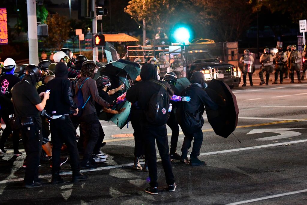 Protesters use umbrellas as shields from projectiles fired by Los Angeles County sheriff's deputies moving in to disperse a crowd of demonstrators gathered to protest again in the wake of Dijon Kizzee's killing, outside the South L.A. sheriff's station on Sept. 8, 2020 in Los Angeles, California. (FREDERIC J. BROWN/AFP via Getty Images)