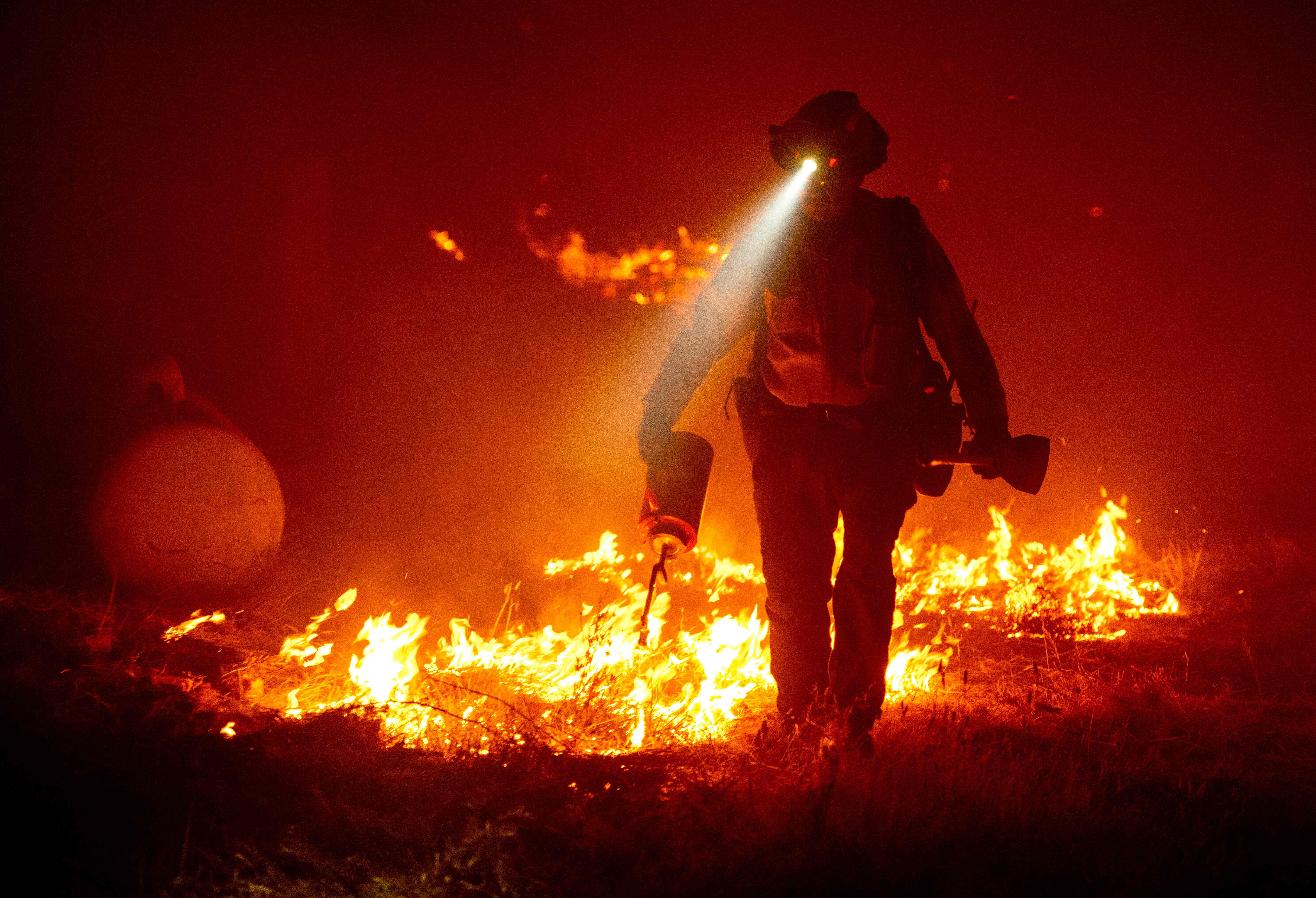 Firefighters cut defensive lines and light backfires to protect structures behind a CalFire fire station during the Bear fire, part of the North Lightning Complex fires in the Berry Creek area of unincorporated Butte County, California on September 9, 2020. - (JOSH EDELSON/AFP via Getty Images)