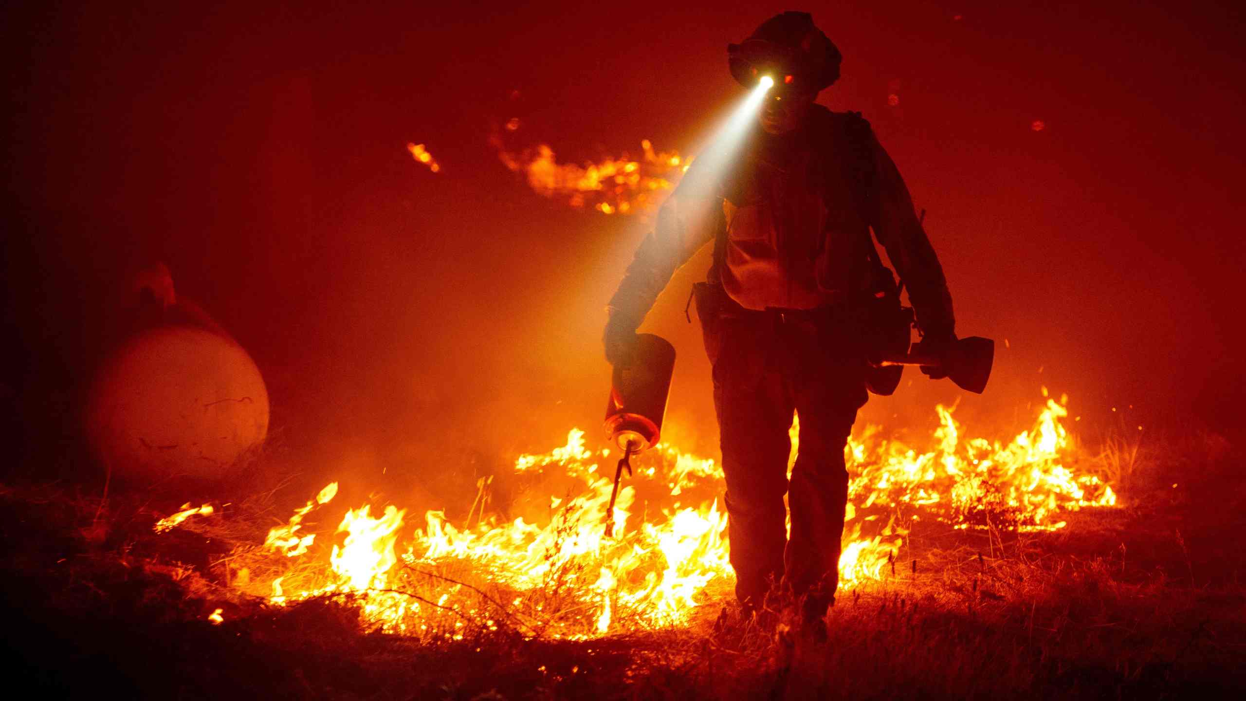 Firefighters cut defensive lines and light backfires to protect structures behind a CalFire fire station during the Bear fire, part of the North Lightning Complex fires in the Berry Creek area of unincorporated Butte County, California on Sept. 9, 2020. (JOSH EDELSON/AFP via Getty Images)