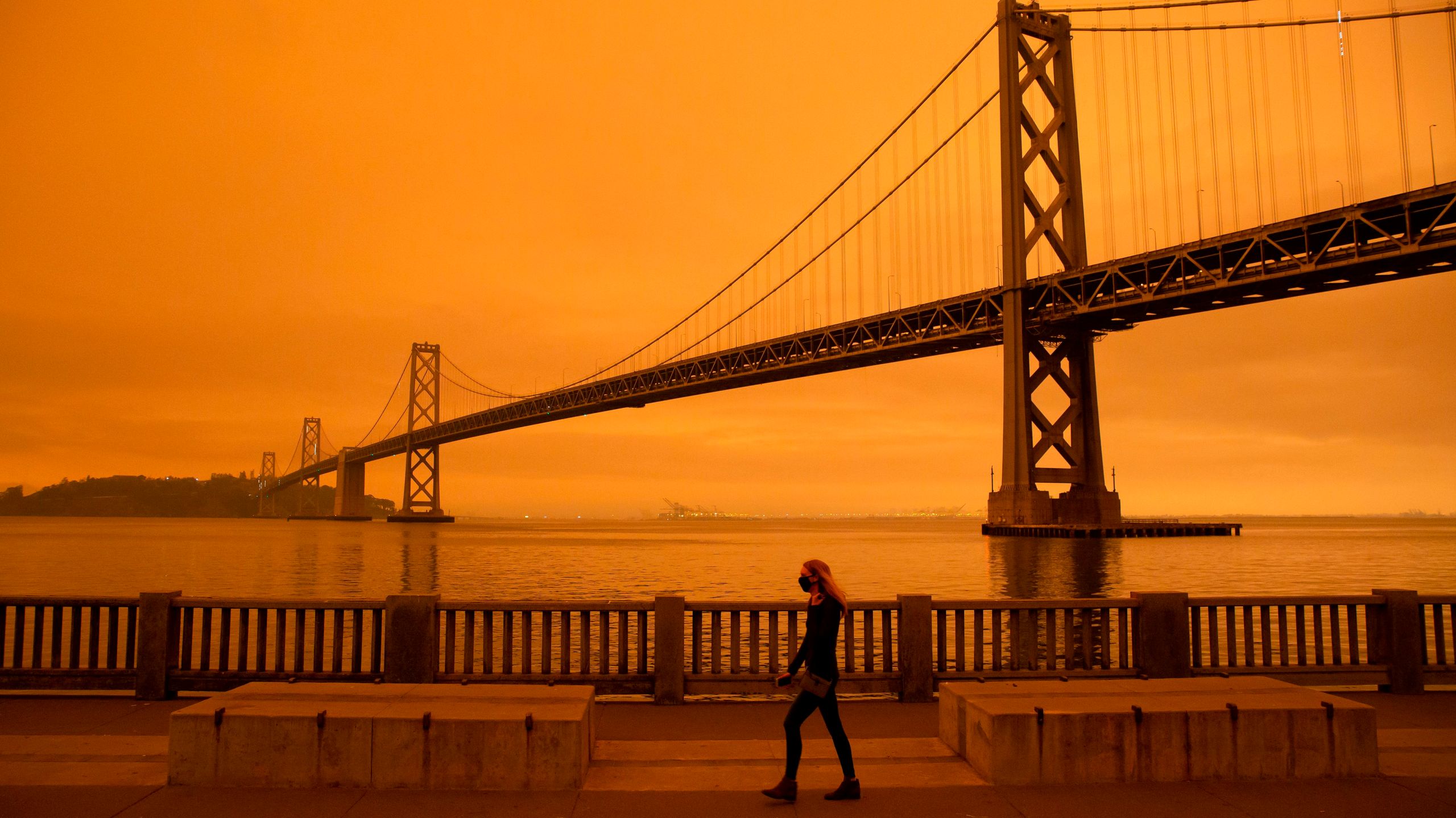 A woman walks along The Embarcadero under an orange smoke-filled sky in San Francisco on Sept. 9, 2020. (Brittany Hosea-Small / AFP / Getty Images)