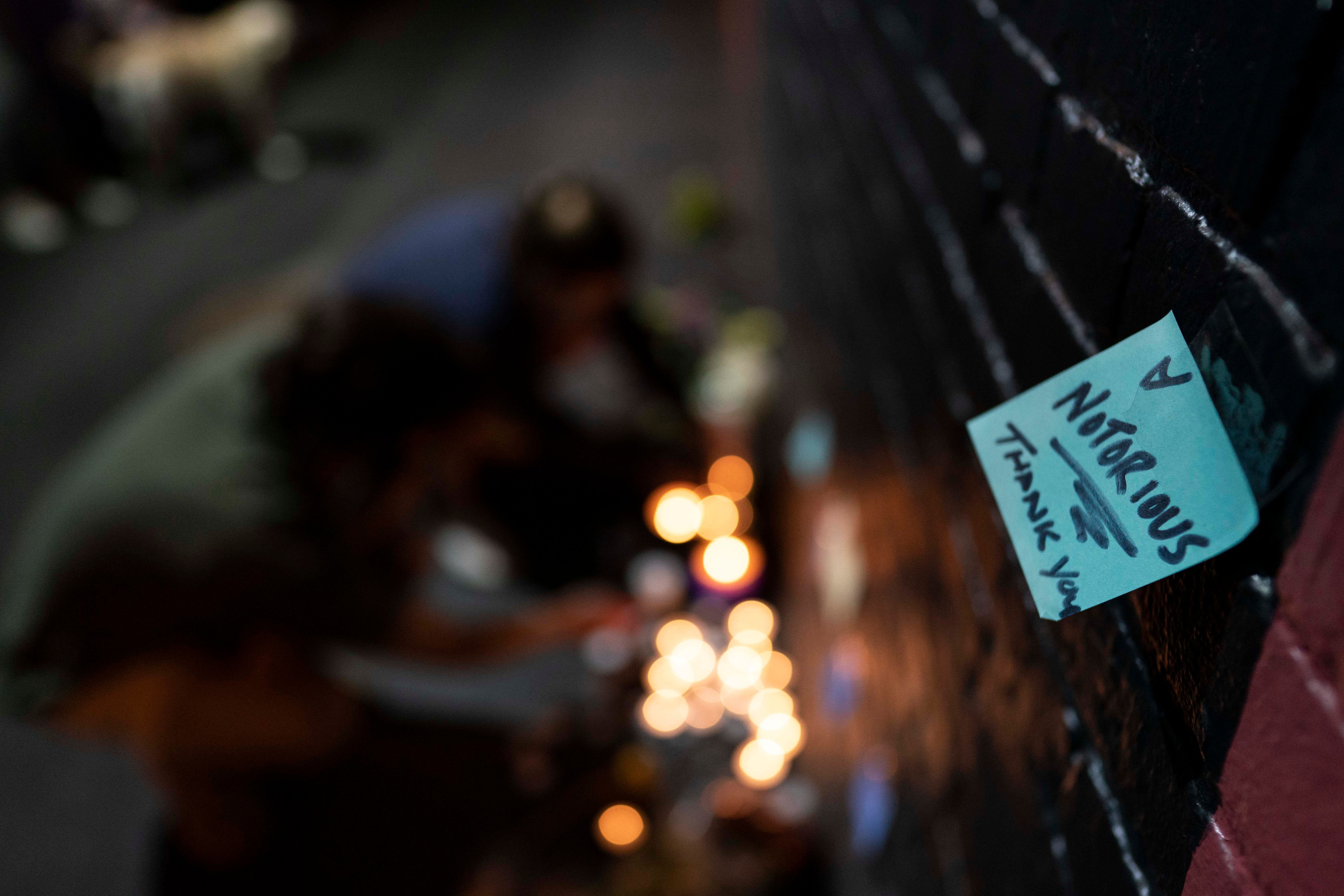 A note is placed near mourners lighting candles below a mural of late U.S. Supreme Court Justice Ruth Bader Ginsburg by artist Rose Jaffe, in Washington, D.C., late on Sept. 18, 2020. (ALEX EDELMAN/AFP via Getty Images)