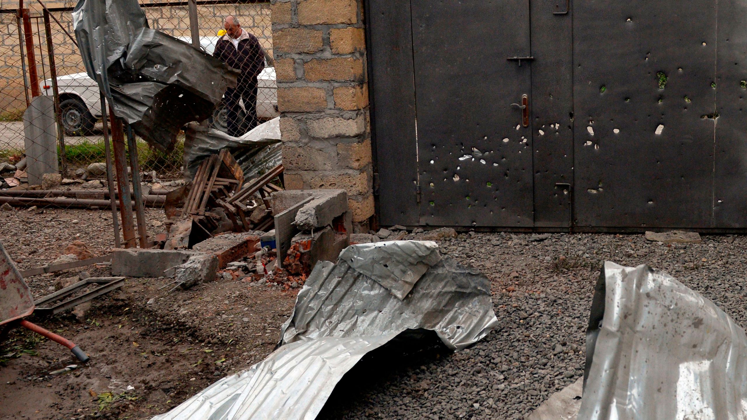 A man stands near a gate which is said was damaged in recent shelling during clashes between Armenian separatists and Azerbaijan over the breakaway Nagorny Karabakh region, on the outskirts of the Azerbaijani city of Tartar on Sept. 28, 2020. (Tofik BABAYEV / AFP via Getty Images)