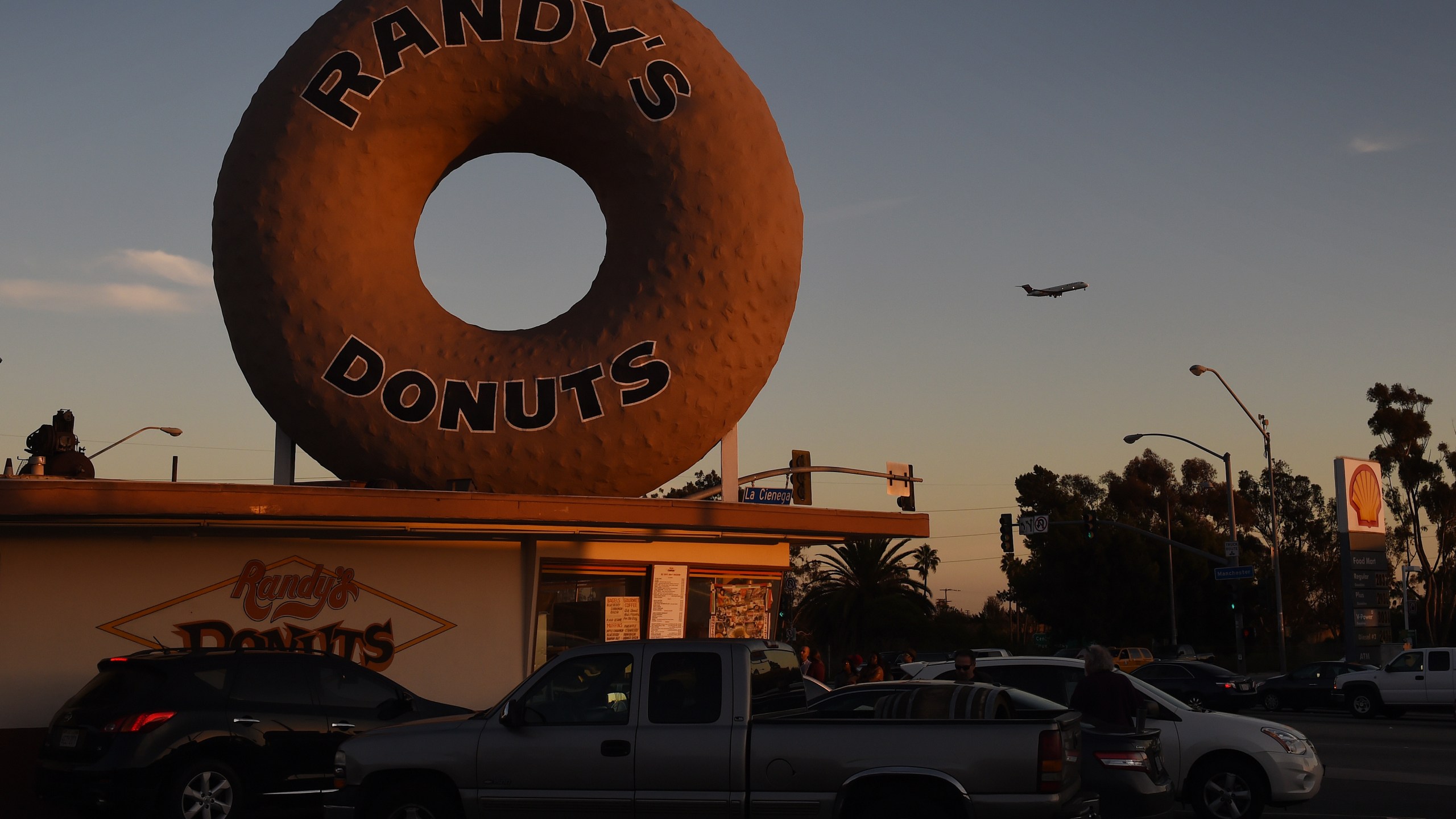 A Swissair plane flies past Randy's Donuts which is an iconic landmark in the city of Inglewood, as it makes its descent into Los Angeles International Airport, California on January 24, 2016. The recent announcement that the St. Louis Rams football team will relocate to a new stadium in Inglewood has started a property boom in the surrounding area. AFP PHOTO / MARK RALSTON / AFP / MARK RALSTON (Photo credit should read MARK RALSTON/AFP via Getty Images)