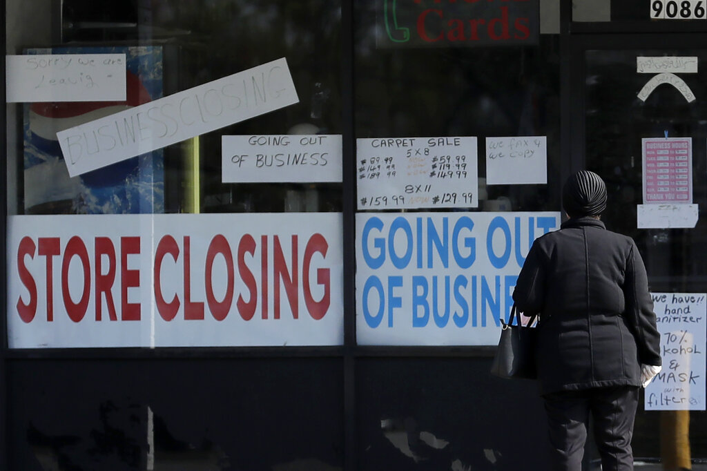 In this file photo, a woman looks at signs at a store closed due to COVID-19 in Niles, Ill., Wednesday, May 13, 2020. (AP Photo/Nam Y. Huh)