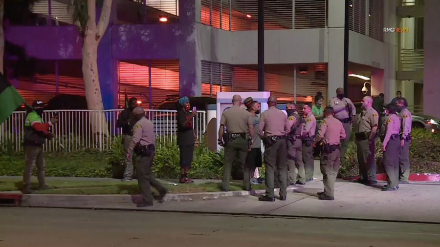 A small group of protesters and a reporter speak to L.A. County sheriff's deputies outside St. Francis Medical Center in Lynwood. (RMG News)