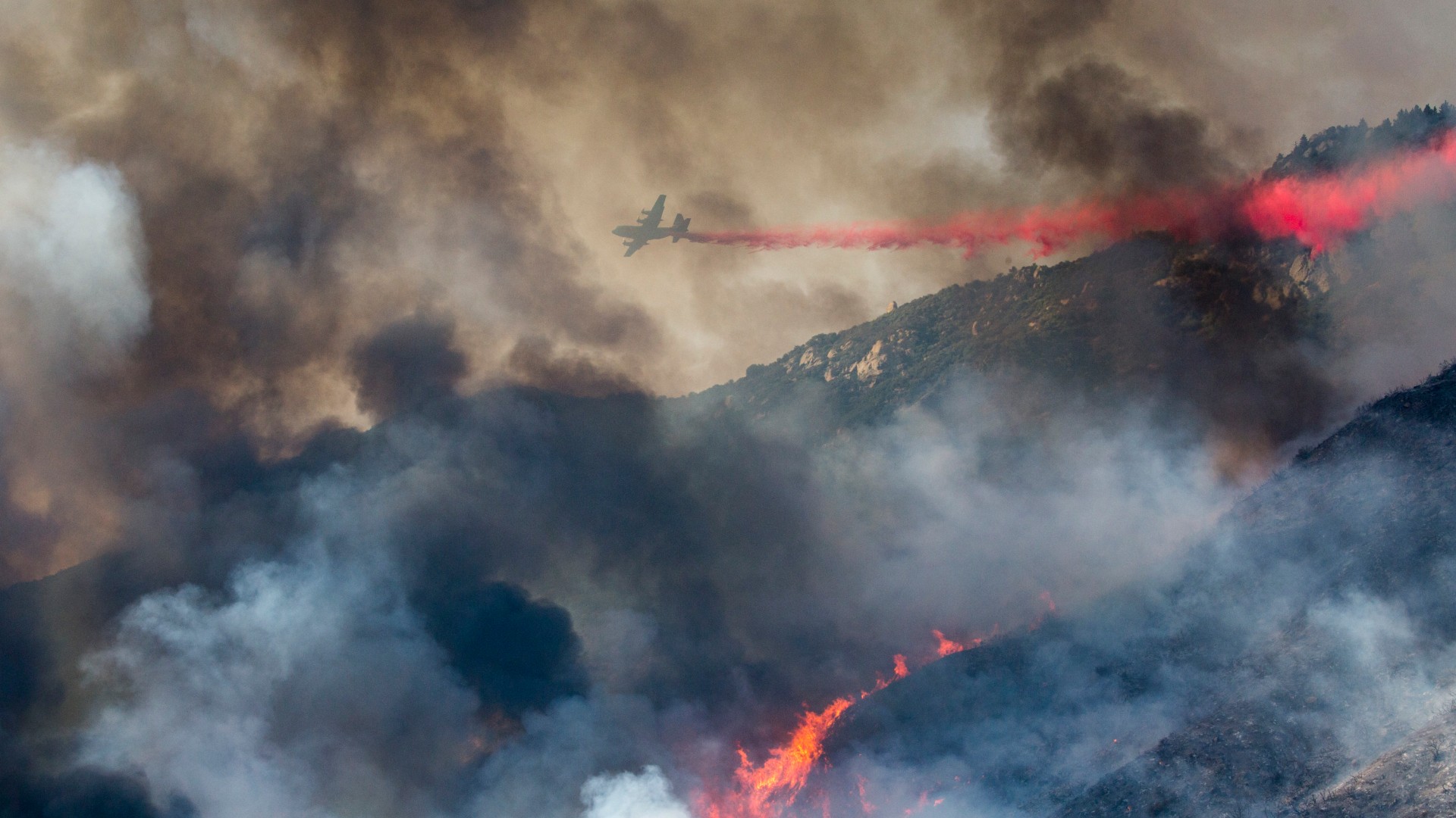 In this Saturday, Sept. 5, 2020 file photo, an air tanker drops fire retardant on a hillside wildfire in Yucaipa, Calif. (AP Photo/Ringo H.W. Chiu)