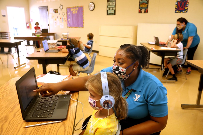 Denecia Boone, a teacher with the YMCA, helps Maya Haldeman, foreground, with an exercise at the Anza Elementary School campus in Torrance. (Genaro Molina / Los Angeles Times)