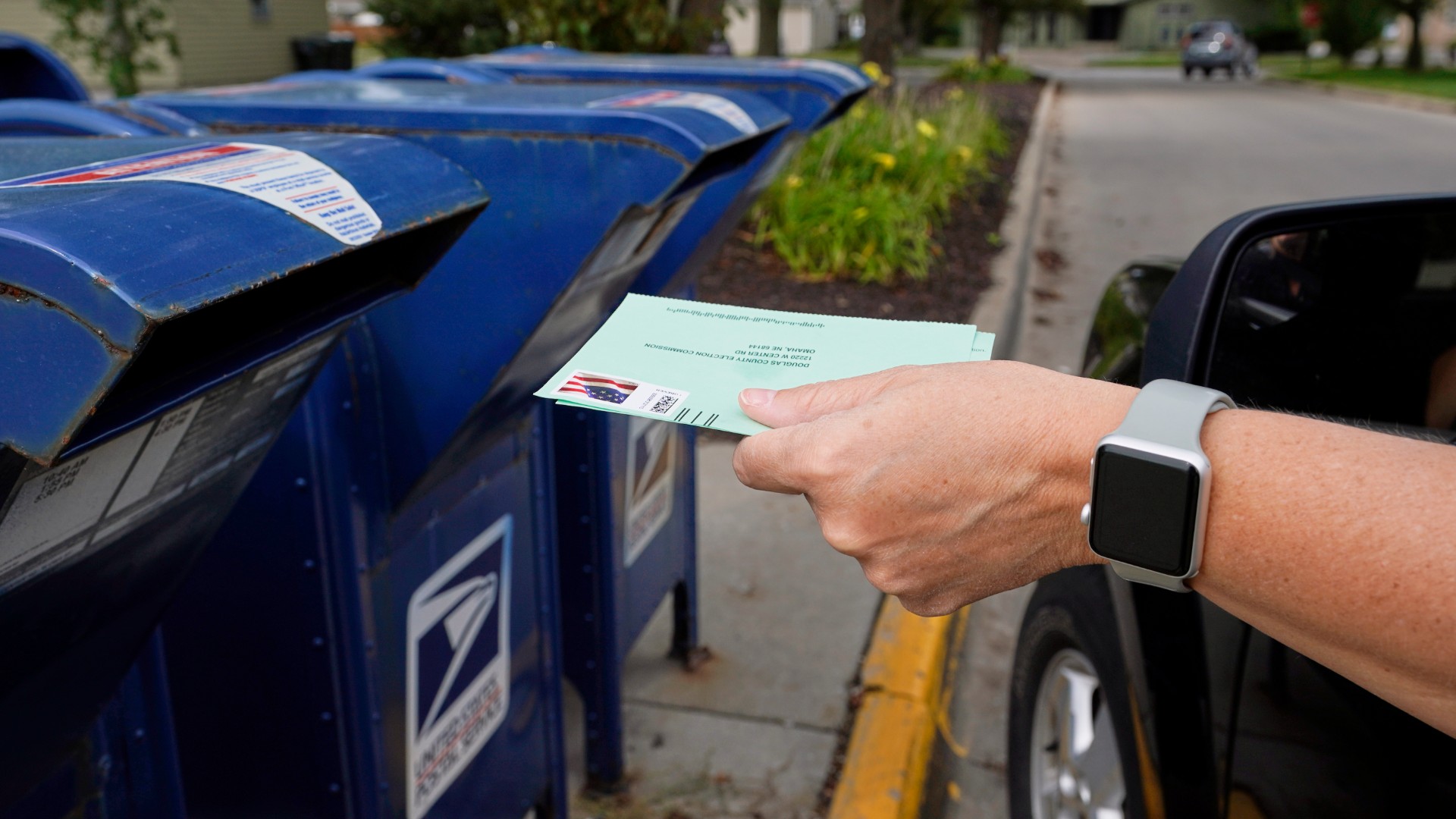 In this Tuesday, Aug. 18, 2020, file photo, a person drops applications for mail-in-ballots into a mail box in Omaha, Neb. (AP Photo/Nati Harnik, File)