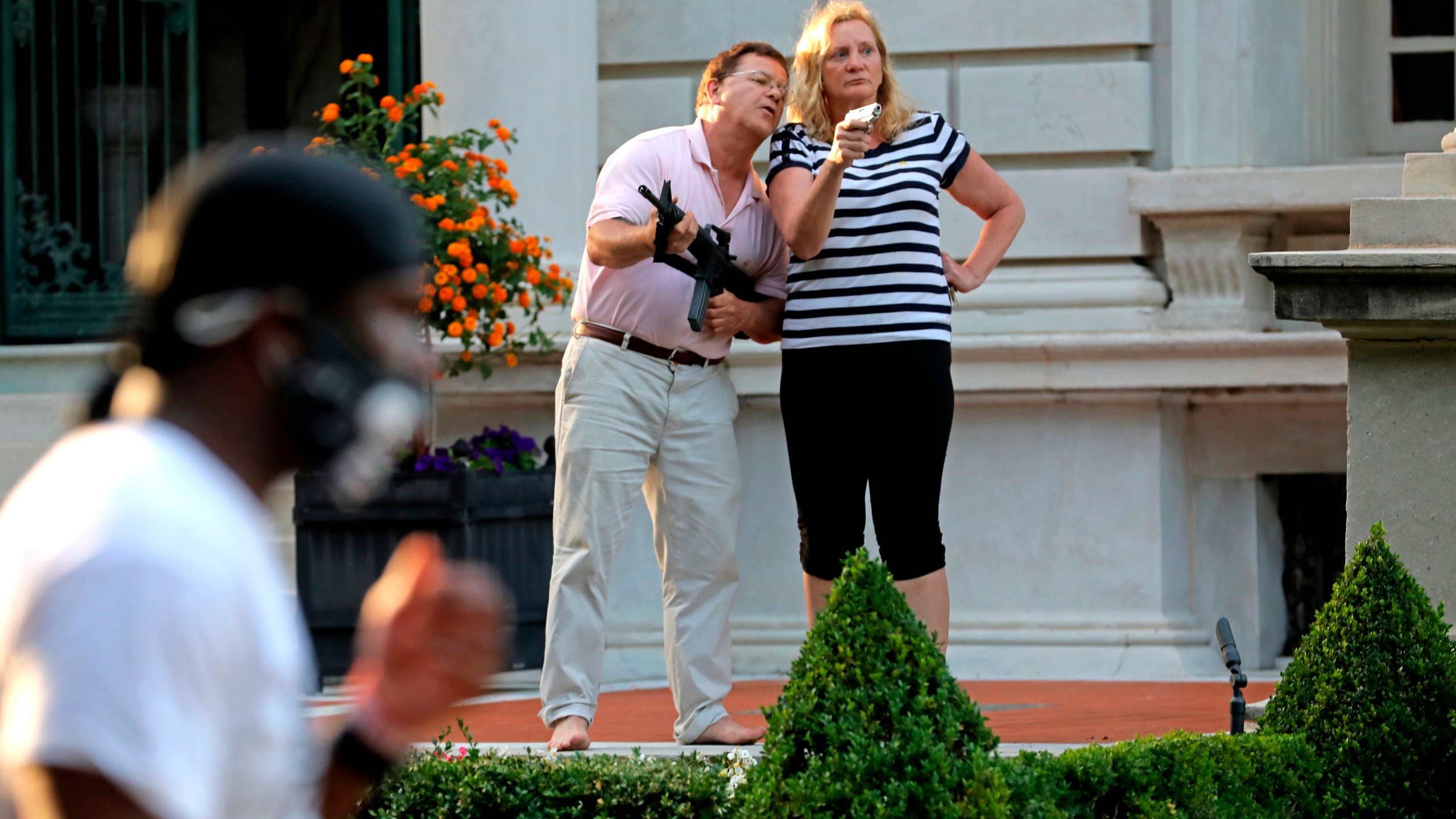 Armed homeowners Mark and Patricia McCloskey, standing in front their house along Portland Place confront protesters marching to St. Louis Mayor Lyda Krewson's house in the Central West End of St. Louis on June 28, 2020. (Laurie Skrivan/St. Louis Post-Dispatch via AP File)