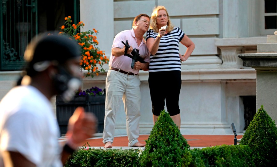 Armed homeowners Mark and Patricia McCloskey, standing in front their house along Portland Place confront protesters marching to St. Louis Mayor Lyda Krewson's house in the Central West End of St. Louis on June 28, 2020. (Laurie Skrivan/St. Louis Post-Dispatch via AP File)