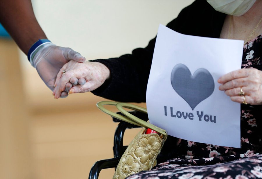 In this July 17, 2020 file photo, a senior citizen holds the hand of a care coordinator at a Health facility in Miami. (AP Photo/Wilfredo Lee)