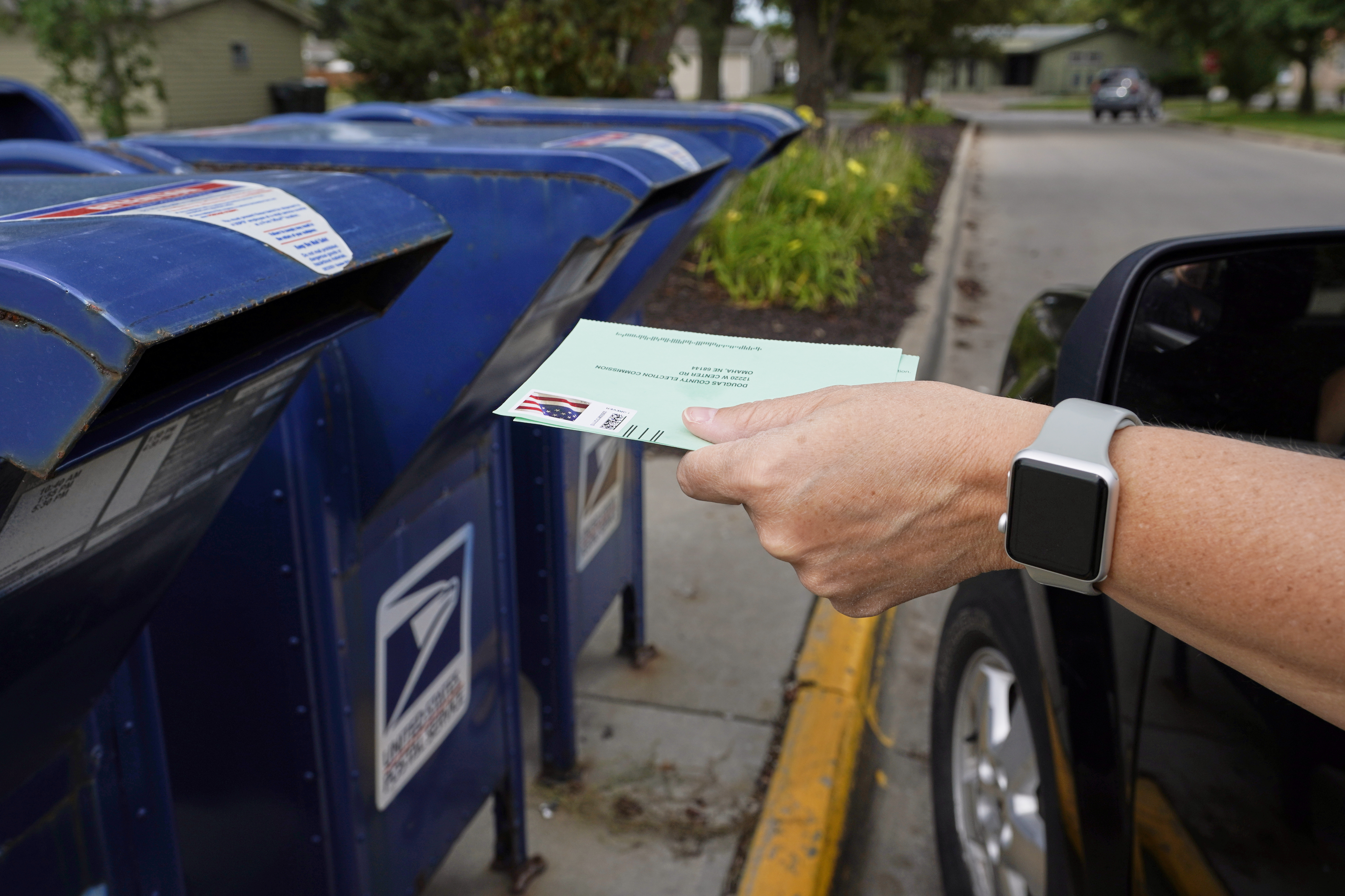 In this Tuesday, Aug. 18, 2020, file photo, a person drops applications for mail-in-ballots into a mail box in Omaha, Neb. (Nati Harnik/AP Photo)