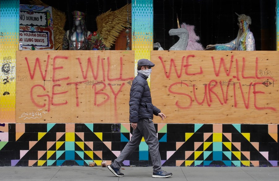 A man wears a face mask while walking past signs posted over windows of a store in the Haight-Ashbury district in San Francisco, Saturday, April 18, 2020. California's death count from the coronavirus surpassed 15,000 on Sunday, Sept. 20, even as the state saw widespread improvement in infection levels. (AP Photo/Jeff Chiu)