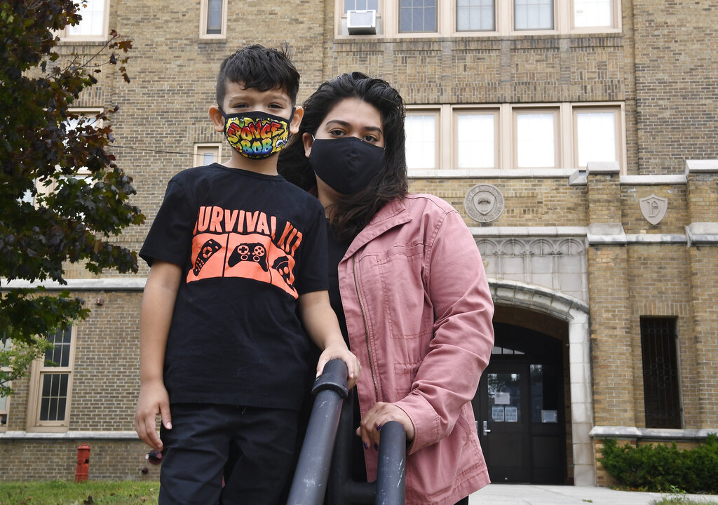 Kristina Negron poses for a photograph with her son, Mason Negron, 6, at his Pleasant Valley Elementary school on Sept. 29, 2020, in Schenectady, N.Y. Negron was laid off from her job as an aide for a special education class at Schenectady High School, due to budget cuts. (AP Photo/Hans Pennink)