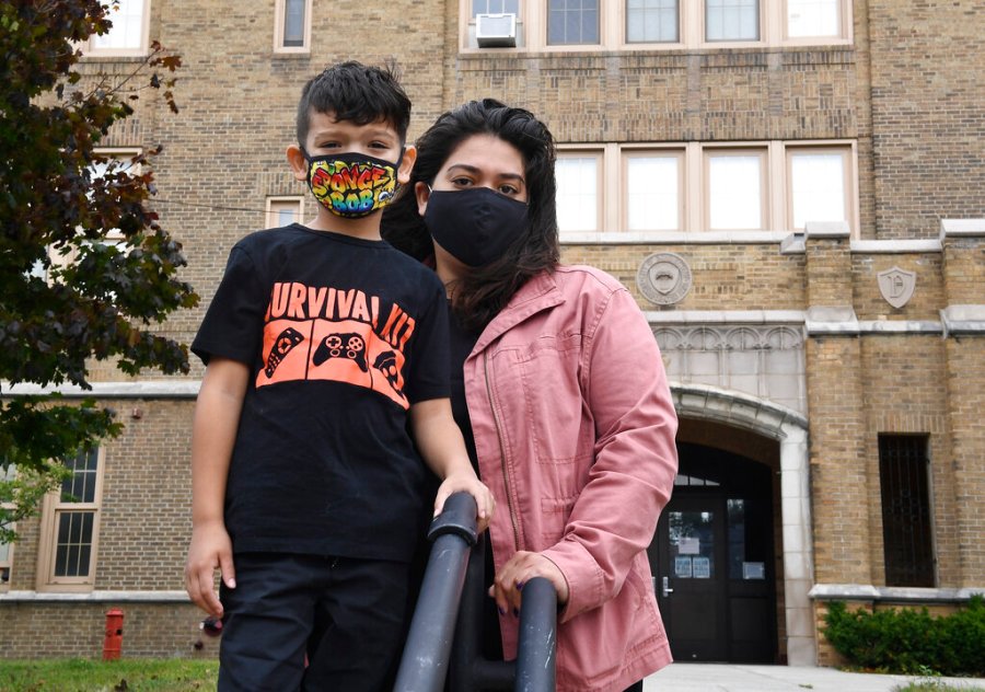 Kristina Negron poses for a photograph with her son, Mason Negron, 6, at his Pleasant Valley Elementary school on Sept. 29, 2020, in Schenectady, N.Y. Negron was laid off from her job as an aide for a special education class at Schenectady High School, due to budget cuts. (AP Photo/Hans Pennink)