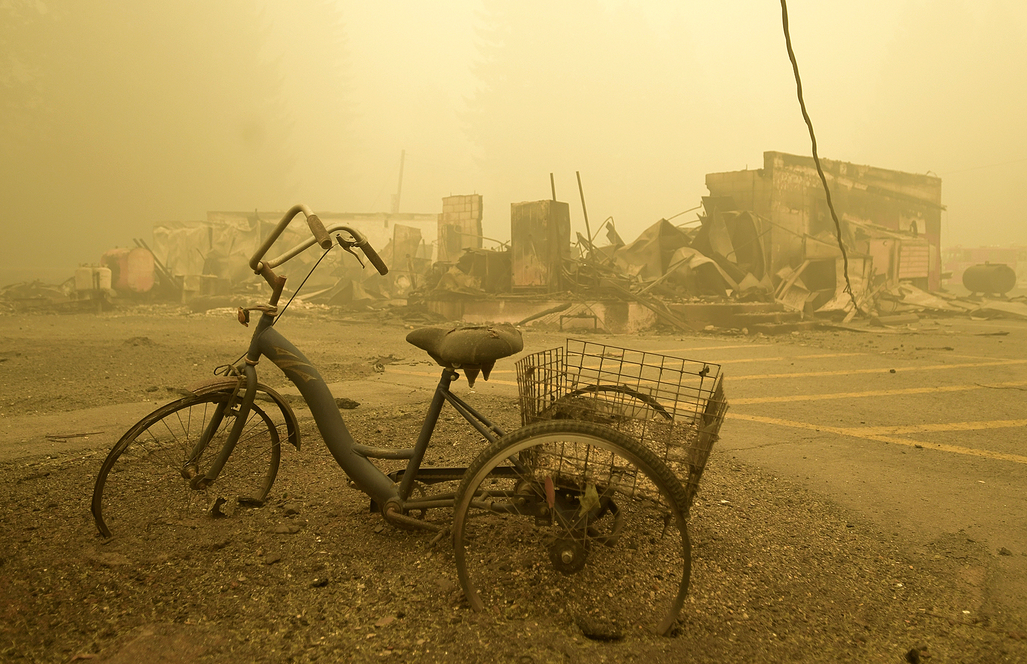 In this Sept. 11, 2020 file photo, a trike stands near the burnt remains of a building destroyed by a wildfire near the Lake Detroit Market in Detroit, Ore. The blaze was one of multiple fires that burned across the state last month. Three Pacific Northwest law firms have filed a class action lawsuit against Pacific Power and its parent company, Portland-based PacifiCorp, alleging that the power company failed to shut down its power lines despite a historic wind event and extremely dangerous wildfire conditions. (Mark Ylen/Albany Democrat-Herald via AP, File)