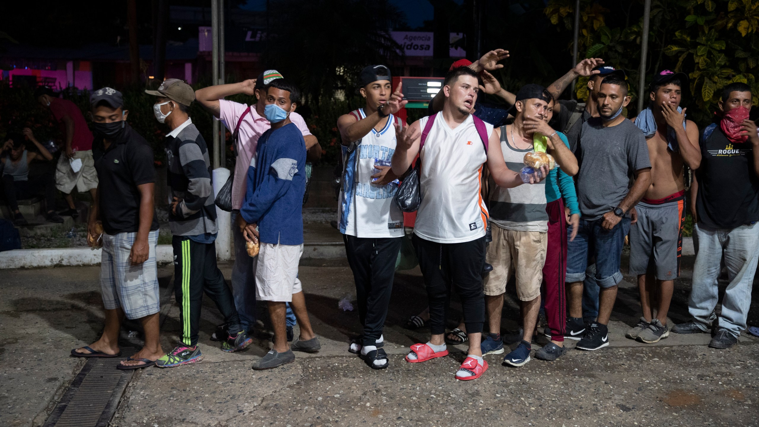 Migrants from Honduras stand in line waiting for aid during their journey to the United States-Mexican border, in Morales, Guatemala, Thursday, Oct. 1, 2020. (AP Photo/Moises Castillo)