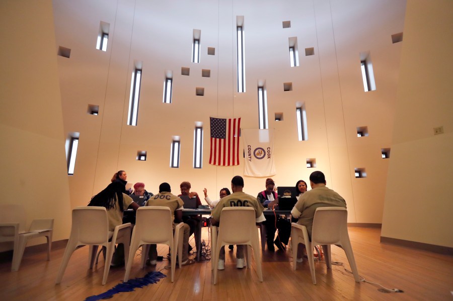 In this March 14, 2020, file photo, Chicago election officials register inmates to vote and participate in early voting for the Illinois primary at a Cook County Jail chapel. (AP Photo/Charles Rex Arbogast, File)