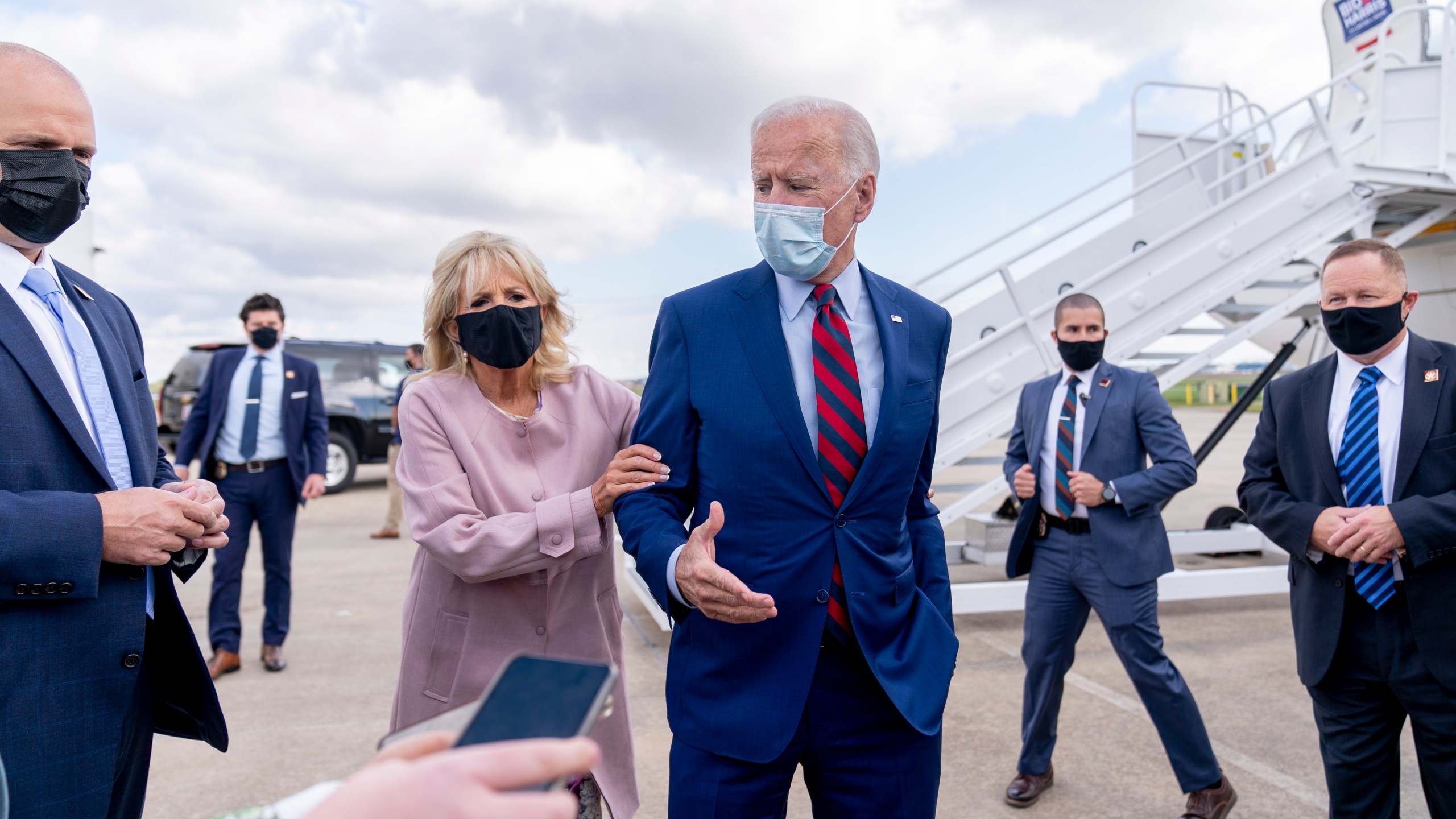 Jill Biden moves her husband, Democratic presidential candidate former Vice President Joe Biden, back from members of the media as he speaks outside his campaign plane at New Castle Airport in New Castle, Del., Monday, Oct. 5, 2020, to travel to Miami for campaign events. (AP Photo/Andrew Harnik)