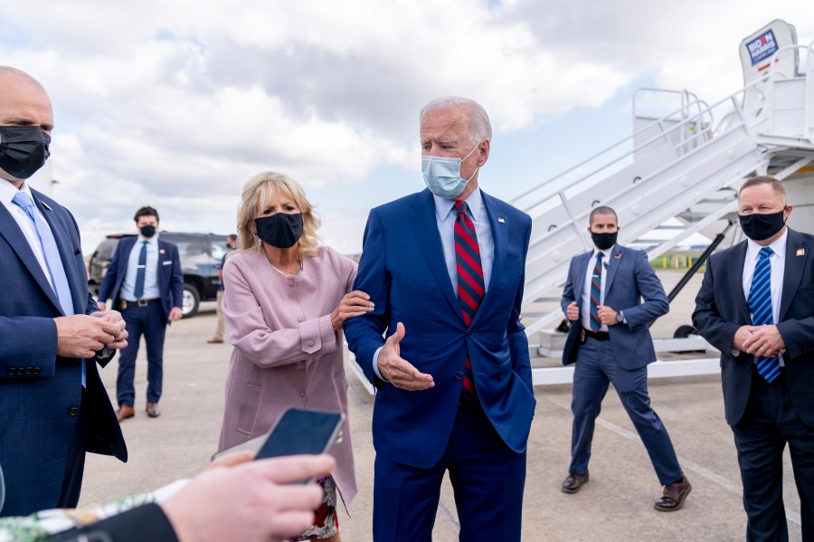 Jill Biden moves her husband, Democratic presidential candidate former Vice President Joe Biden, back from members of the media as he speaks outside his campaign plane at New Castle Airport in New Castle, Del., Monday, Oct. 5, 2020, to travel to Miami for campaign events. (AP Photo/Andrew Harnik)