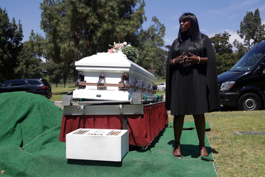 In this July 21, 2020, file photo, Candy Boyd, owner of Boyd Funeral Home, speaks to family members at an interment for Lydia Nunez, who died from COVID-19, at the Rose Hills Cemetery in Whittier, Calif. (AP Photo/Marcio Jose Sanchez, File)