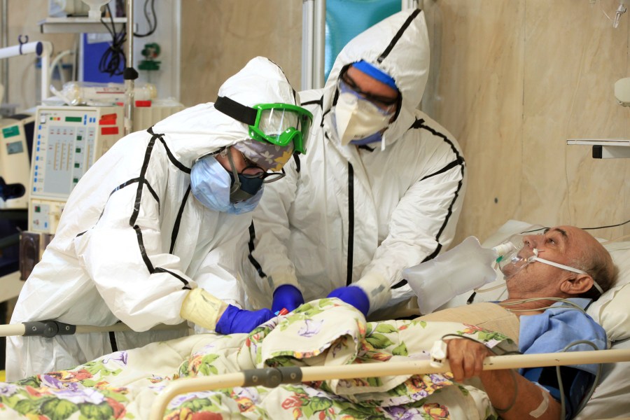 In this Wednesday, Oct. 14, 2020, photo provided by the Iranian Health Ministry, medics tend to a COVID-19 patient at the Shohadaye Tajrish Hospital in Tehran, Iran. (Akbar Badrkhani/Iranian Health Ministry via AP)