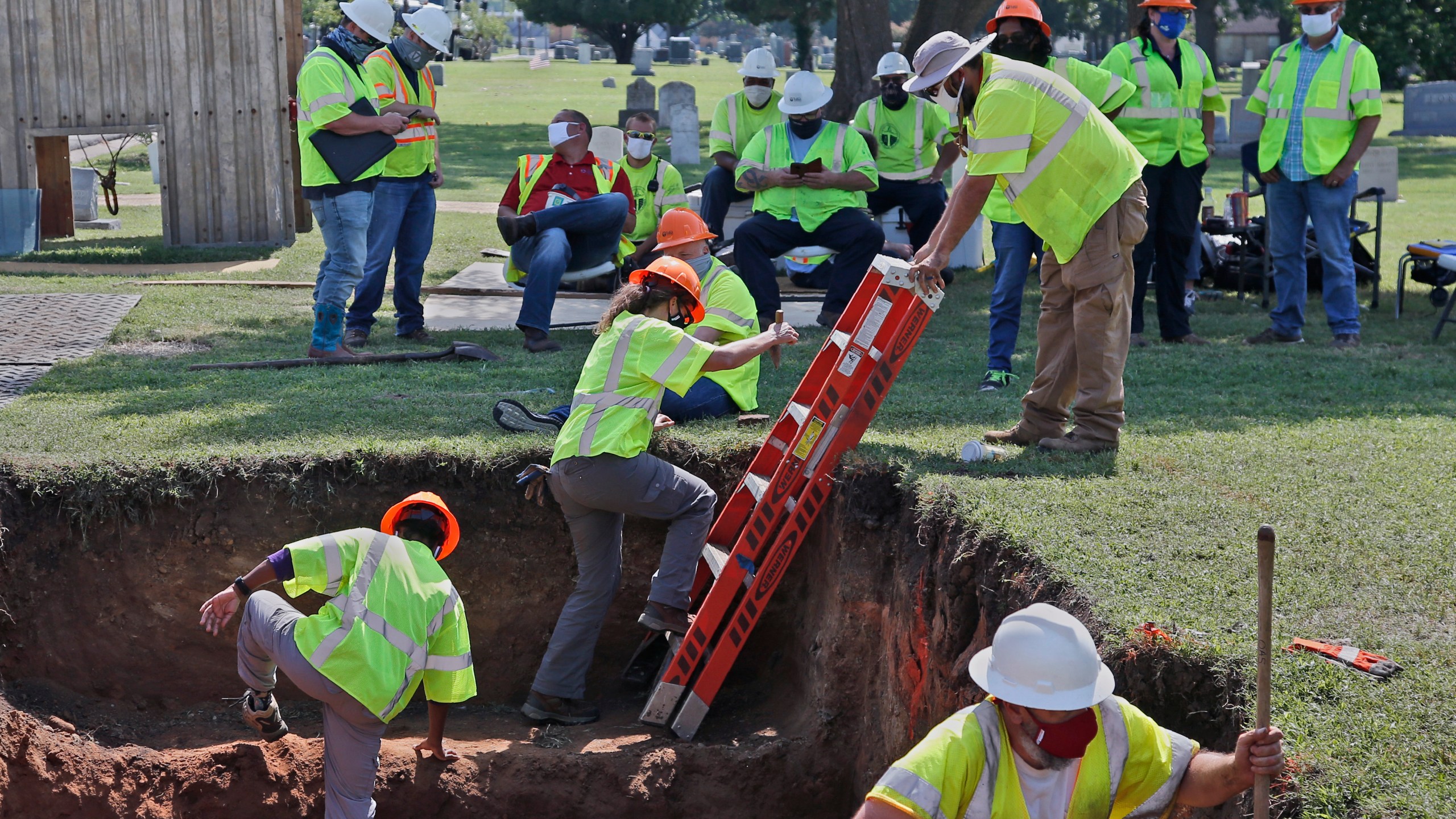 In this July 14, 2020, file photo, workers climb out of the excavation site as work continues on a potential unmarked mass grave from the 1921 Tulsa Race Massacre, at Oaklawn Cemetery in Tulsa, Okla. (AP Photo/Sue Ogrocki File)