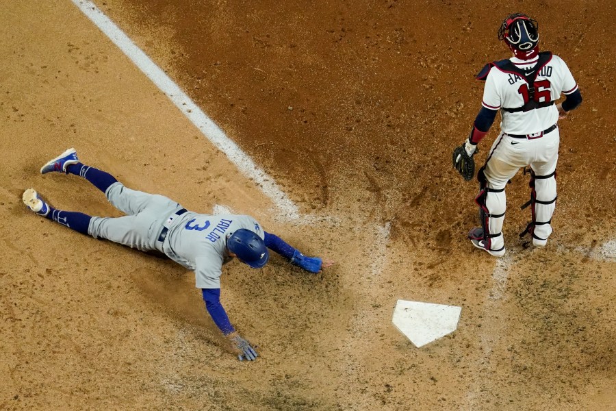 Los Angeles Dodgers' Chris Taylor scores past Atlanta Braves catcher Travis d'Arnaud on a hit by Mookie Betts during the seventh inning in Game 5 of a baseball National League Championship Series Friday, Oct. 16, 2020, in Arlington, Texas. (AP Photo/David J. Phillip)