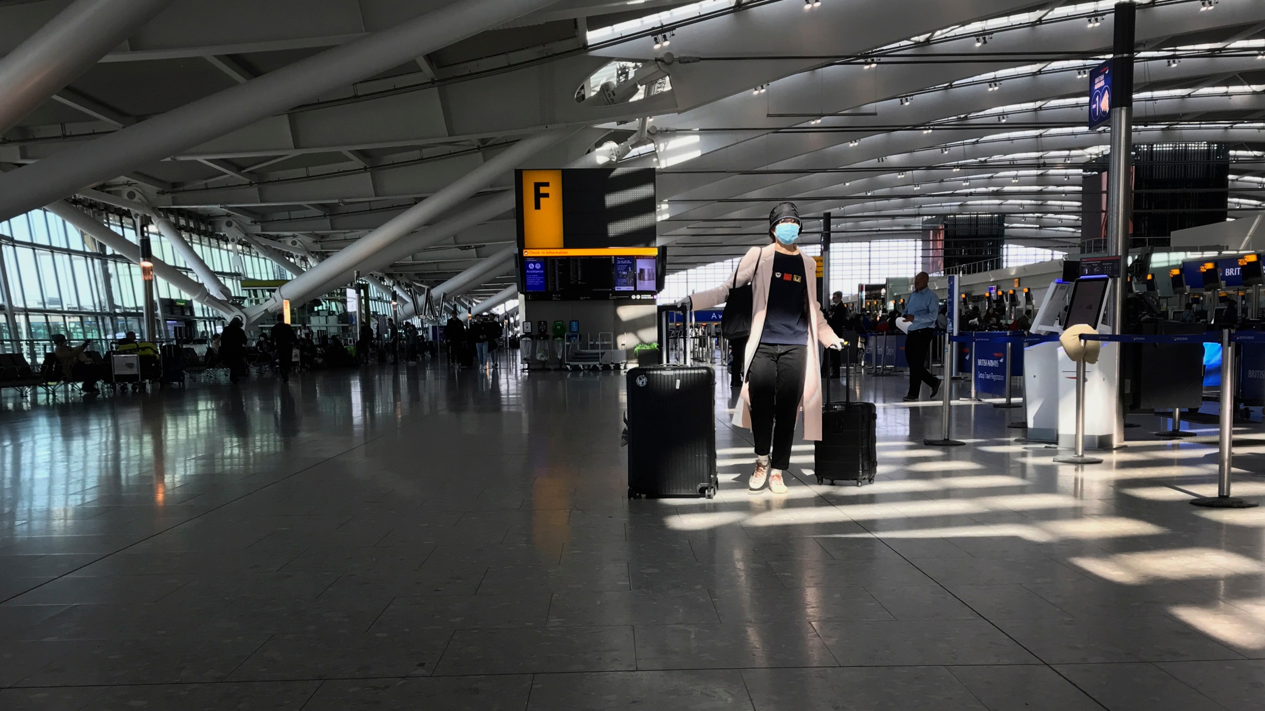 In this Tuesday, March 24, 2020 file photo, a woman wears a mask as she walks through a quieter than usual Heathrow Airport Terminal 5, in London. Air traffic is down 92% this year as travelers worry about catching COVID-19 and government travel bans and quarantine rules make planning difficult. One thing airlines believe could help is to have rapid virus tests of all passengers before departure. (AP Photo/Kirsty Wigglesworth, File)