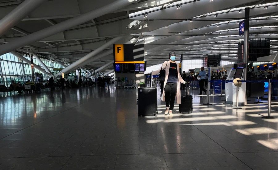 In this Tuesday, March 24, 2020 file photo, a woman wears a mask as she walks through a quieter than usual Heathrow Airport Terminal 5, in London. Air traffic is down 92% this year as travelers worry about catching COVID-19 and government travel bans and quarantine rules make planning difficult. One thing airlines believe could help is to have rapid virus tests of all passengers before departure. (AP Photo/Kirsty Wigglesworth, File)