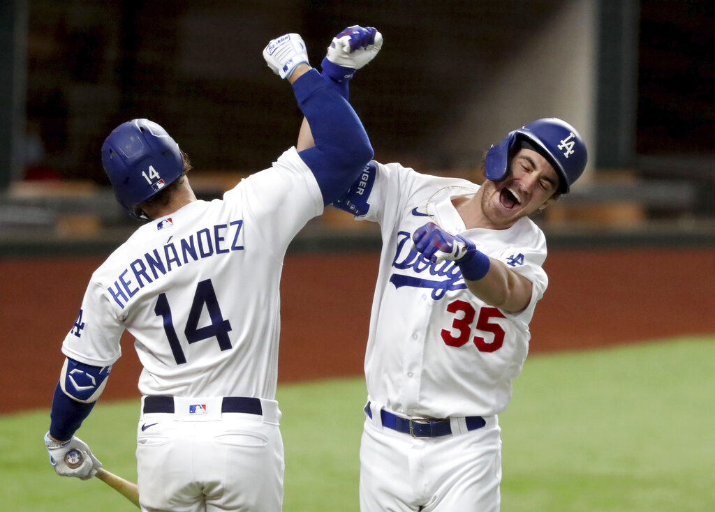 Los Angeles Dodgers' Cody Bellinger, right, celebrates his solo home run with Enrique Hernandez against Atlanta Braves relief pitcher Chris Martin during the seventh inning in Game 7 of a baseball National League Championship Series on Oct. 18, 2020, in Arlington, Texas. (Curtis Compton/Atlanta Journal-Constitution via AP)