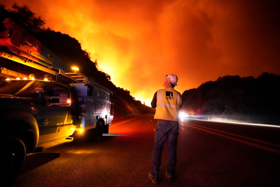 In this Sept. 8, 2020, file photo, a Pacific Gas and Electric worker looks up at the advancing Creek Fire along Highway 168 near Alder Springs, Calif.(AP Photo/Marcio Jose Sanchez, File)